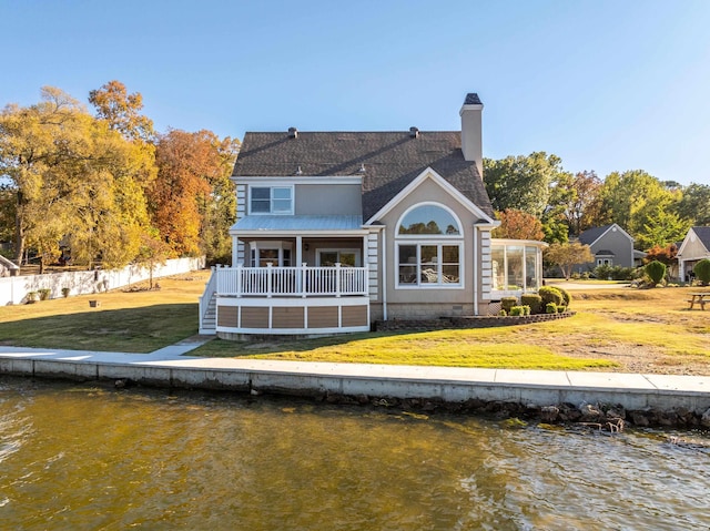 back of property with a water view, fence, a yard, crawl space, and a chimney