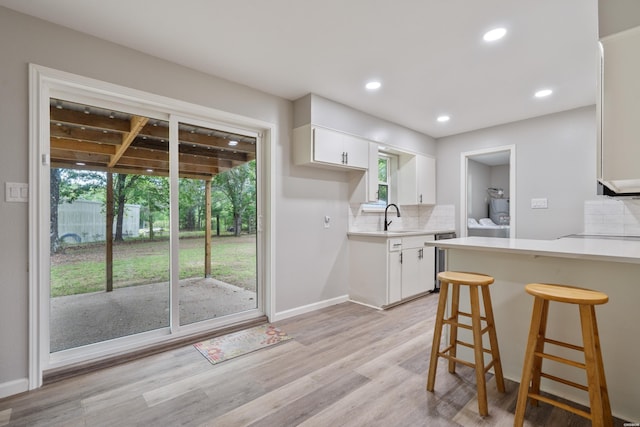 401 Buttrum Rd, Royal, AR 71968 - kitchen featuring white cabinets, tasteful backsplash, light countertops, light wood-type flooring, and a breakfast bar area