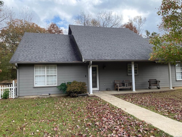 view of front of home with a patio area, a shingled roof, fence, and a front lawn