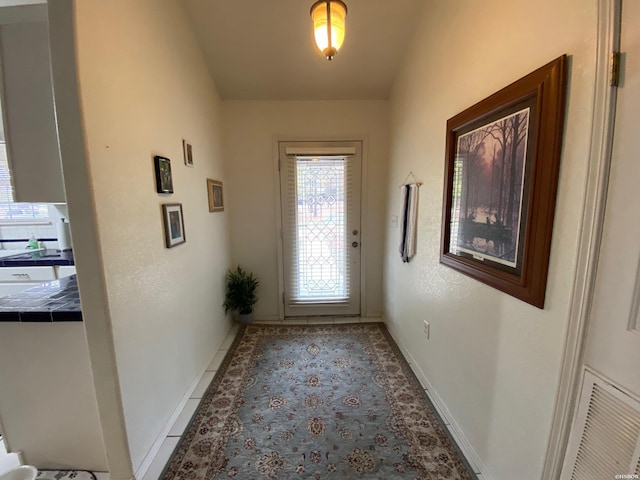 doorway with visible vents, baseboards, and light tile patterned floors