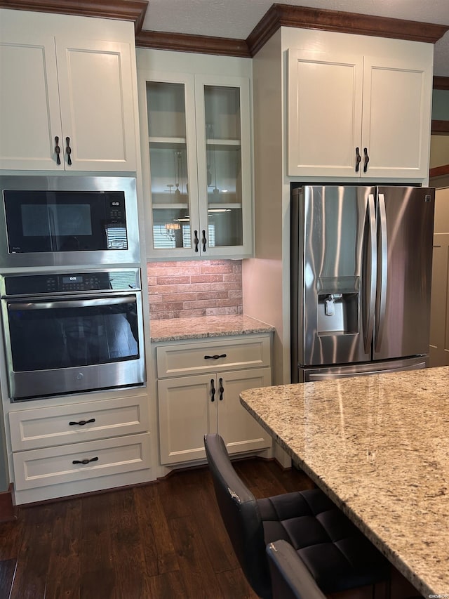1910 Josh Dr, Conway, AR 72034 - kitchen featuring stainless steel appliances, glass insert cabinets, light stone counters, white cabinetry, and dark wood-style floors