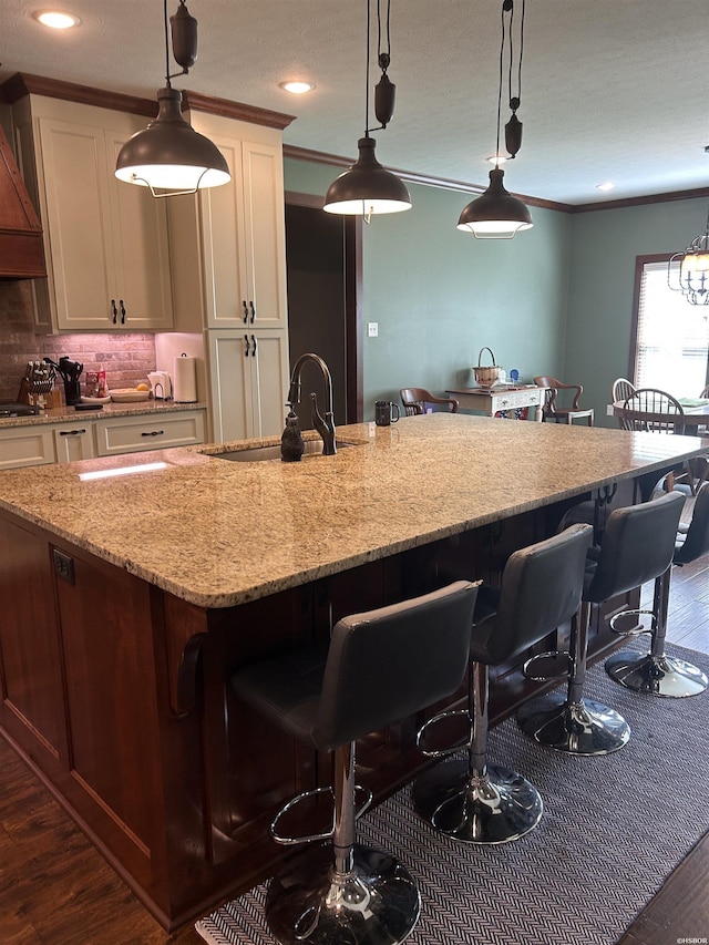 1910 Josh Dr, Conway, AR 72034 - kitchen featuring wall chimney range hood, dark wood-type flooring, light stone counters, a breakfast bar, and tasteful backsplash