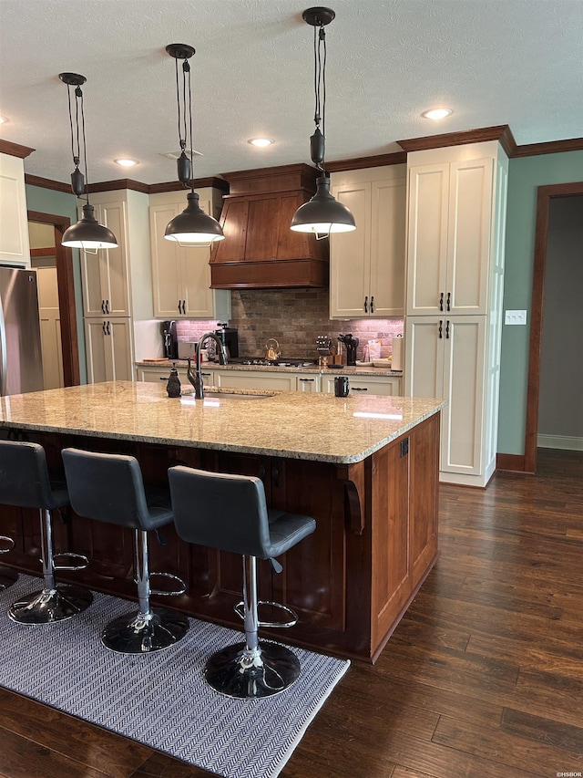 1910 Josh Dr, Conway, AR 72034 - kitchen with custom exhaust hood, crown molding, dark wood finished floors, tasteful backsplash, and light stone counters