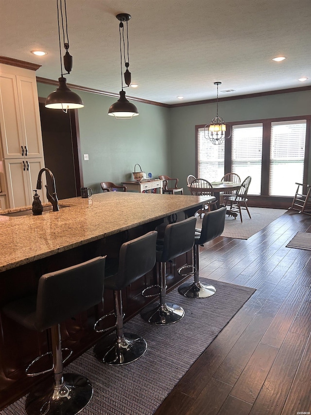 1910 Josh Dr, Conway, AR 72034 - kitchen with white cabinetry, a kitchen breakfast bar, hanging light fixtures, dark wood finished floors, and light stone countertops