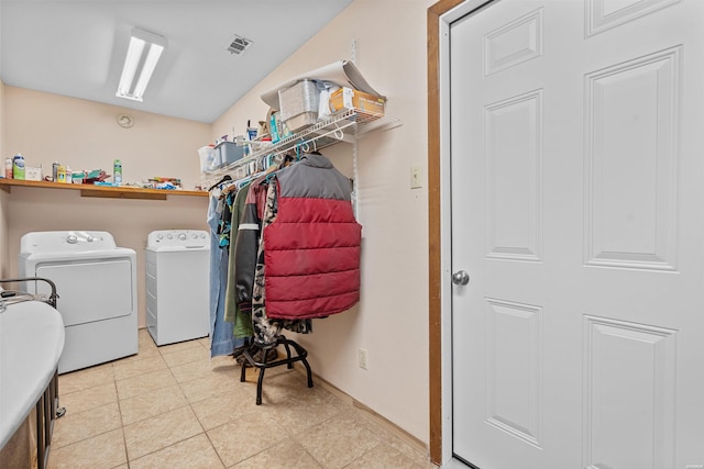 clothes washing area featuring laundry area, light tile patterned flooring, visible vents, and washing machine and clothes dryer