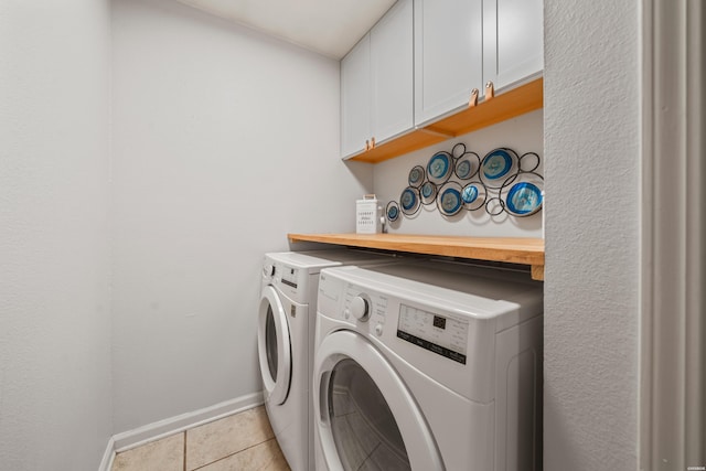 laundry room featuring baseboards, cabinet space, washing machine and dryer, and light tile patterned flooring