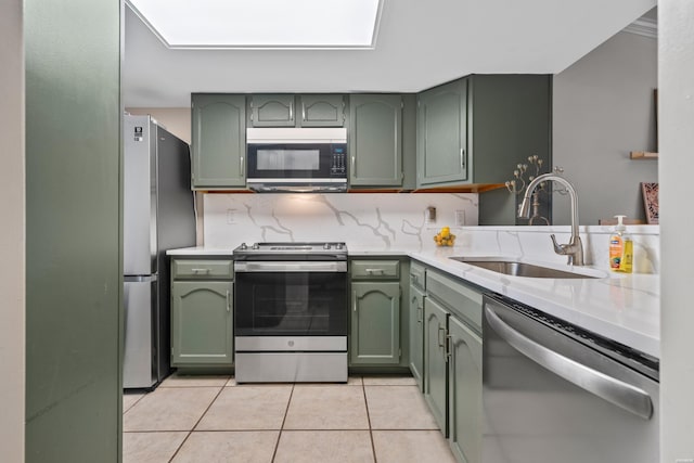 kitchen featuring a sink, stainless steel appliances, light countertops, and green cabinetry