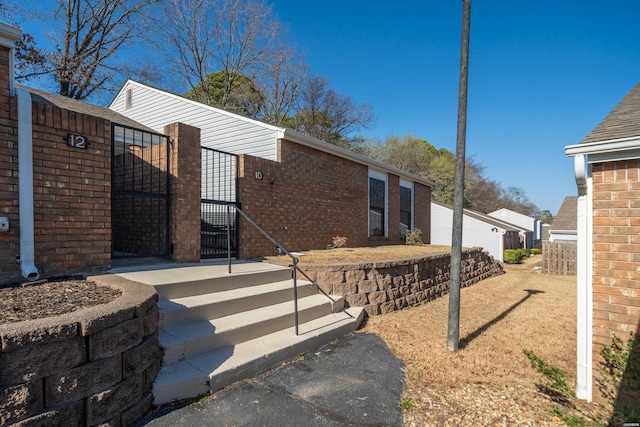 view of side of home featuring brick siding and fence