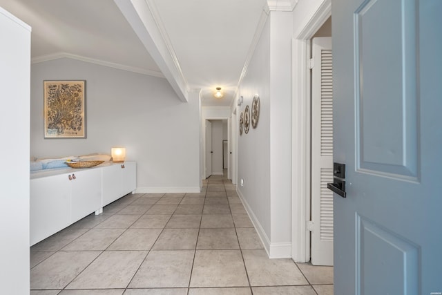 hallway featuring lofted ceiling, light tile patterned flooring, baseboards, and ornamental molding