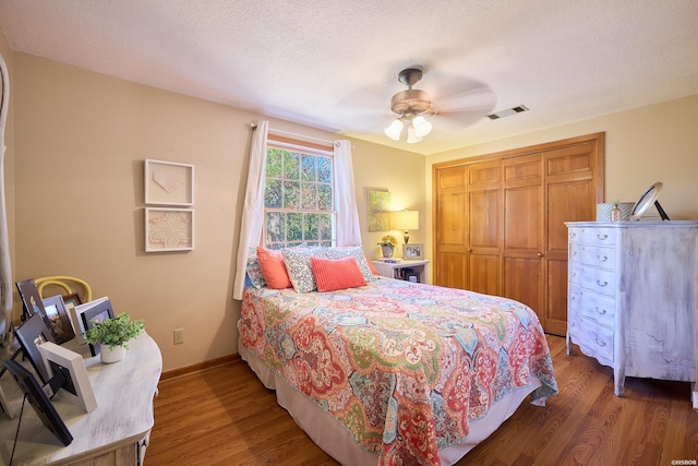 bedroom featuring dark wood-style floors, a closet, a textured ceiling, and visible vents