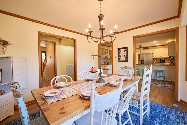 dining space featuring dark wood-style floors, visible vents, a chandelier, and crown molding