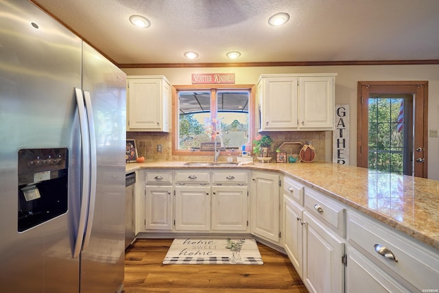 kitchen featuring stainless steel appliances, a sink, white cabinets, dark wood-style floors, and crown molding