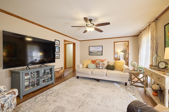 living room with ornamental molding, ceiling fan, and wood finished floors