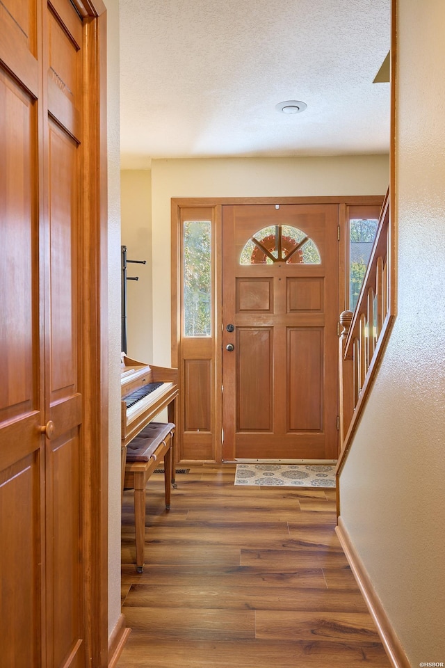 foyer with a textured ceiling, baseboards, and wood finished floors