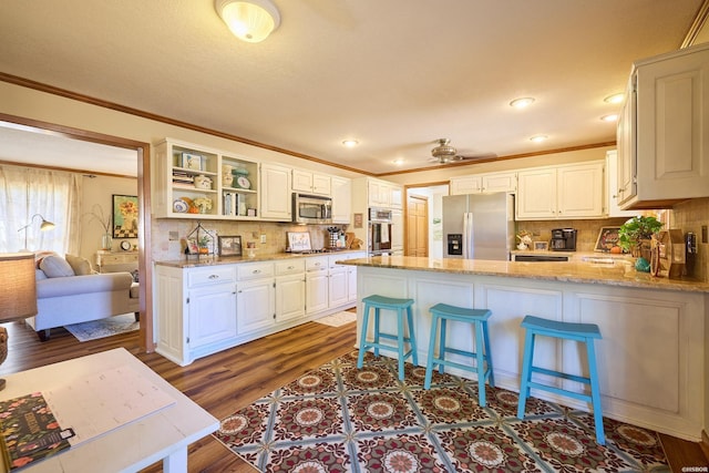 kitchen featuring crown molding, appliances with stainless steel finishes, dark wood-type flooring, white cabinets, and light stone countertops