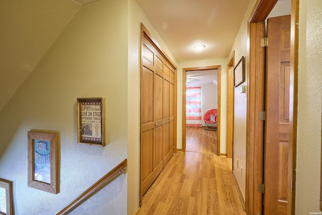 hall with light wood-style flooring and baseboards