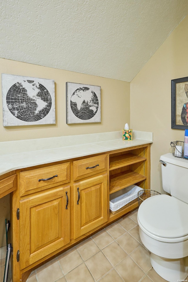 bathroom featuring toilet, lofted ceiling, tile patterned flooring, a textured ceiling, and vanity