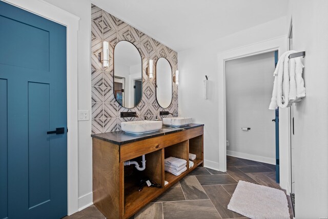 full bath with toilet, a sink, baseboards, and double vanity