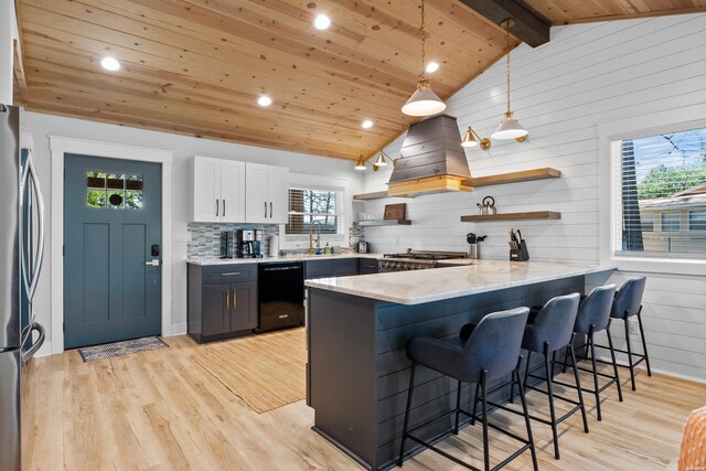 kitchen featuring open shelves, appliances with stainless steel finishes, white cabinets, a peninsula, and a kitchen bar