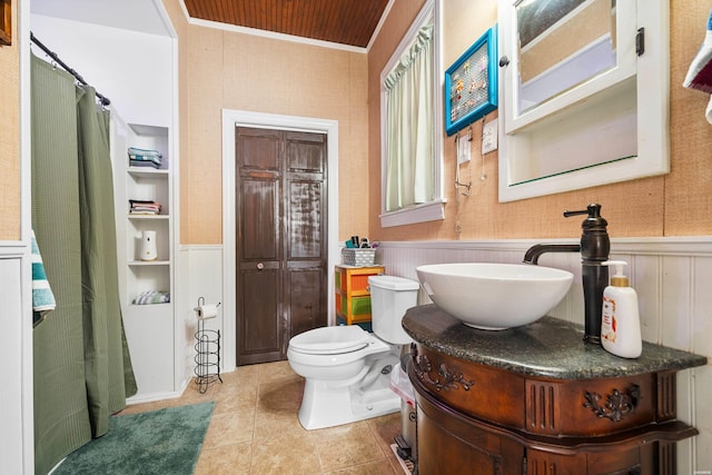bathroom featuring vanity, ornamental molding, tile patterned flooring, a wainscoted wall, and toilet