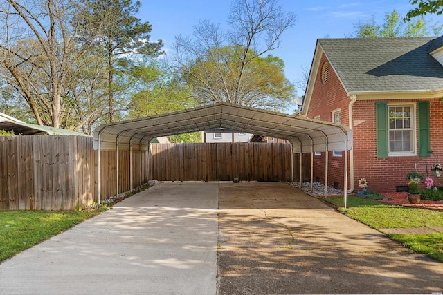 view of car parking featuring a detached carport, fence, and driveway
