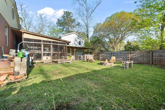 view of yard with a fire pit, a fenced backyard, and a sunroom