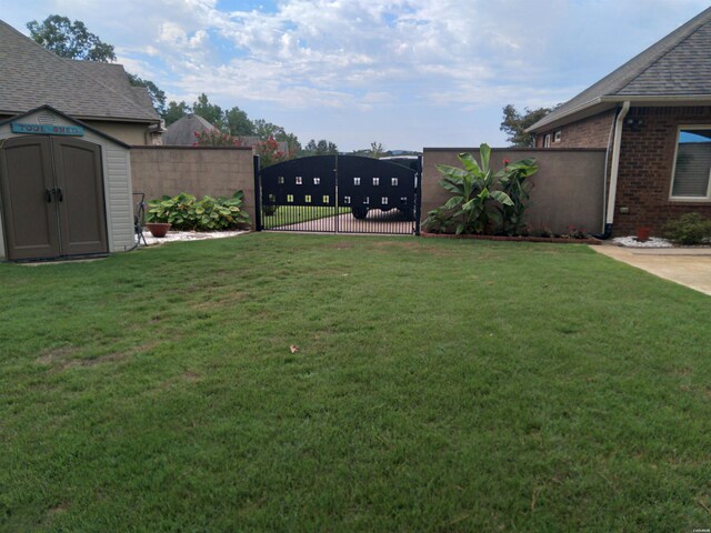 view of yard with a storage shed, an outbuilding, fence, and a gate