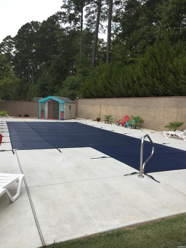 view of pool with an outbuilding, fence, a patio, and a storage unit