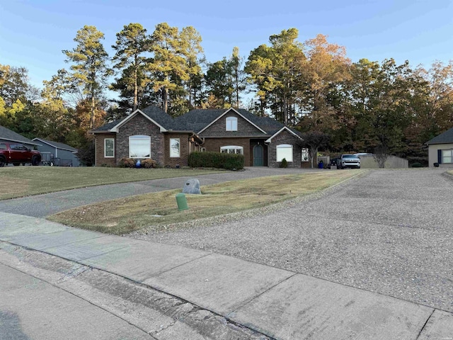 view of front of home featuring a front yard, brick siding, and driveway