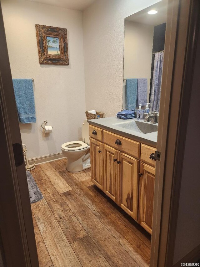 bathroom featuring toilet, wood finished floors, vanity, and baseboards