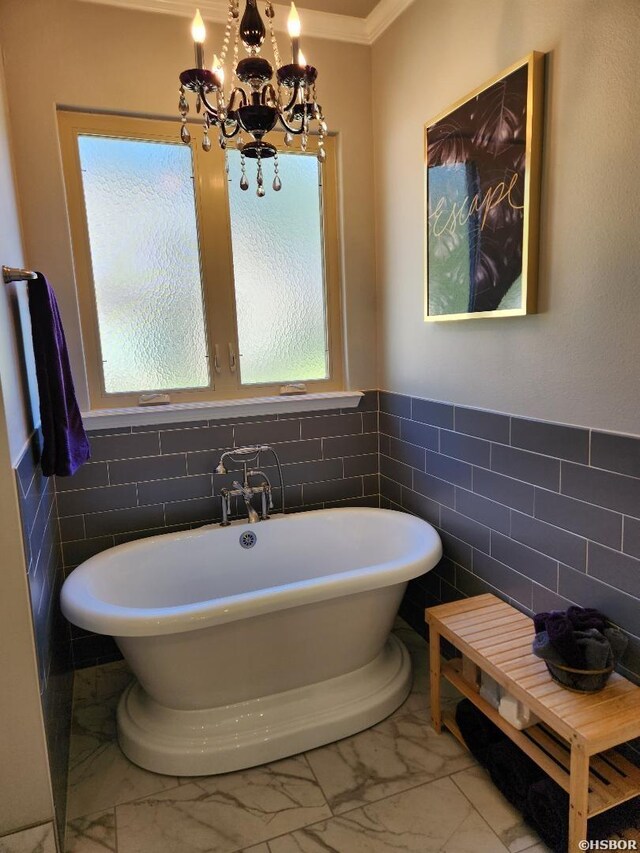 bathroom with a freestanding bath, marble finish floor, wainscoting, and a chandelier