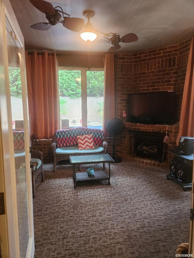 living area with a ceiling fan, a brick fireplace, and carpet flooring