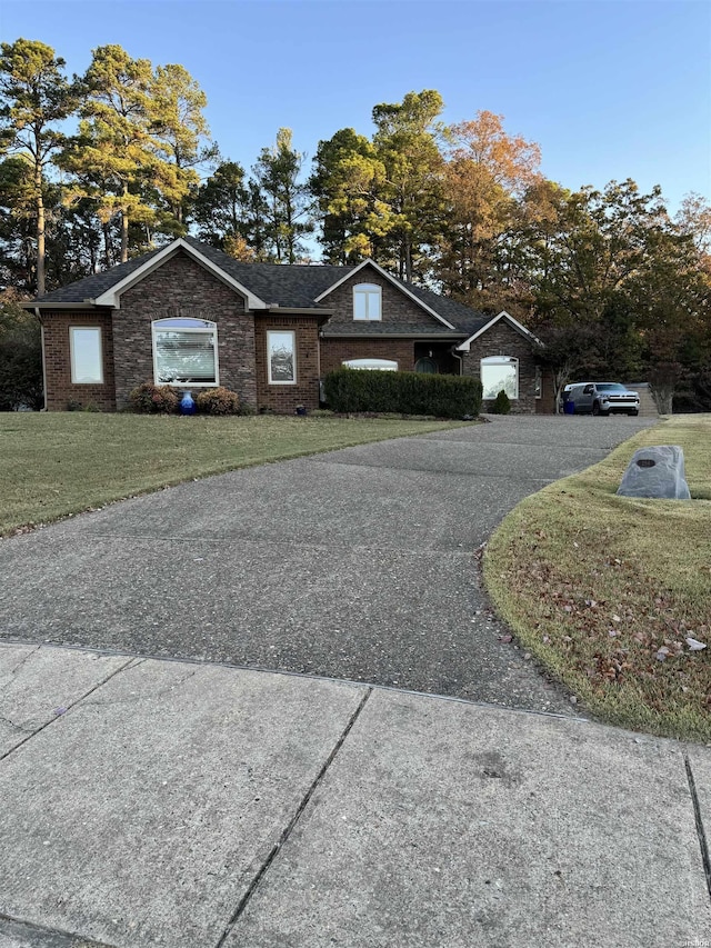 view of front facade featuring brick siding, driveway, and a front lawn