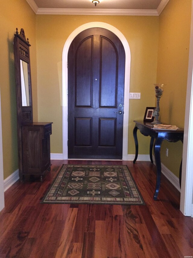 foyer with dark wood-type flooring, arched walkways, crown molding, and baseboards