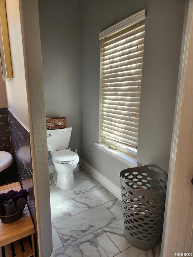 bathroom with marble finish floor, toilet, and baseboards