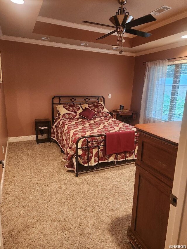 bedroom featuring carpet floors, a raised ceiling, visible vents, ornamental molding, and baseboards