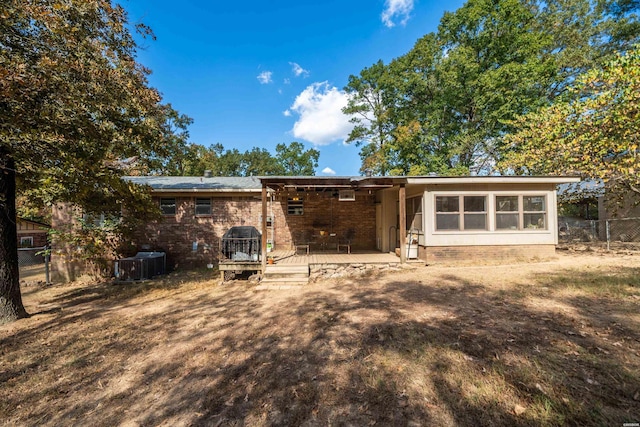 rear view of property with central air condition unit, fence, and brick siding