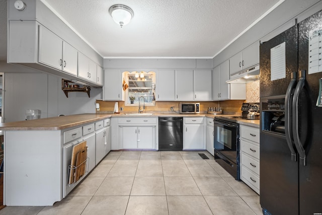 kitchen with black appliances, under cabinet range hood, a sink, a textured ceiling, and light tile patterned floors