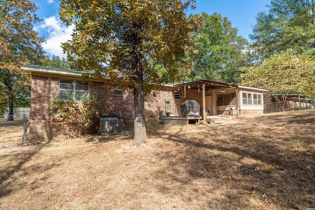 back of house with brick siding, cooling unit, a wooden deck, and fence