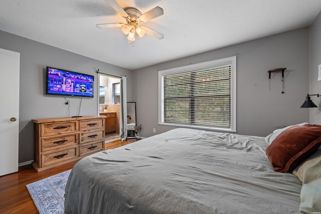 bedroom with a ceiling fan, ensuite bath, wood finished floors, and a textured ceiling