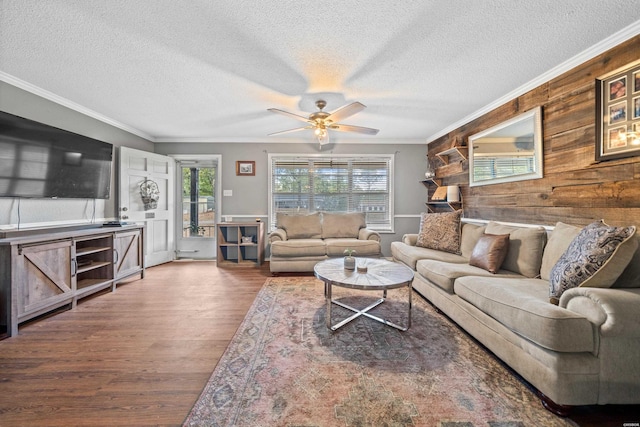 living area featuring ceiling fan, plenty of natural light, wood finished floors, and ornamental molding