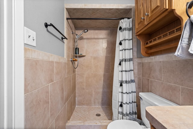 bathroom featuring toilet, a stall shower, and tile walls