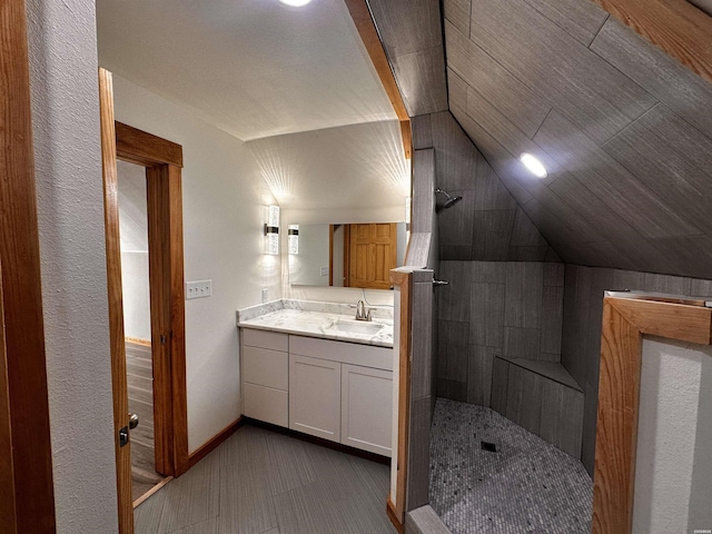 bathroom with lofted ceiling, vanity, baseboards, and a walk in shower