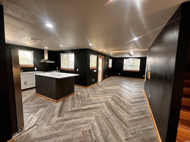 kitchen featuring a kitchen island, open floor plan, white cabinetry, recessed lighting, and wall chimney exhaust hood