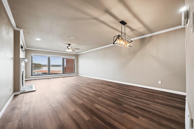 unfurnished living room featuring ceiling fan with notable chandelier, ornamental molding, dark wood finished floors, and baseboards