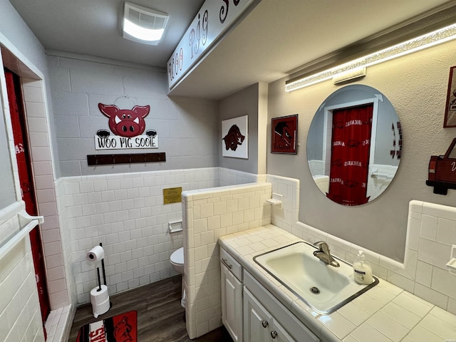 115 Ledgerock Rd, Hot Springs, AR 71913 - bathroom featuring vanity, wood finished floors, toilet, tile walls, and a wainscoted wall