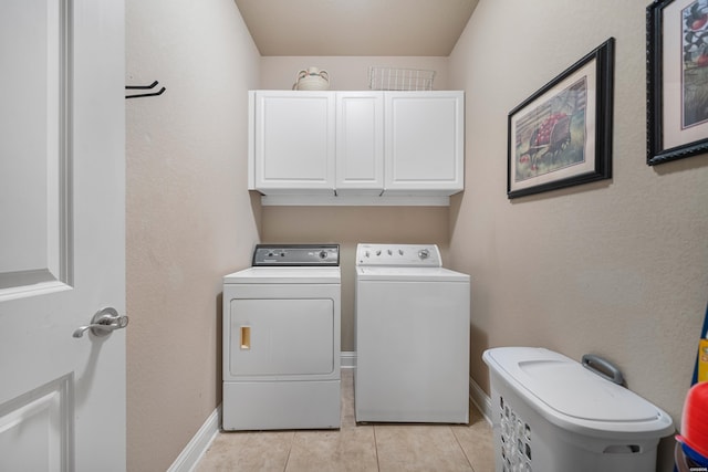 clothes washing area with cabinet space, baseboards, light tile patterned floors, and washer and dryer