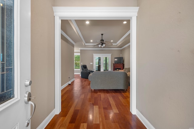 foyer with a raised ceiling, crown molding, ceiling fan, and wood finished floors