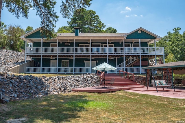 rear view of house featuring ceiling fan, a patio, stairway, and a lawn