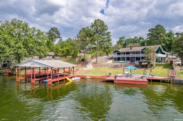 dock area featuring a water view, a lawn, and boat lift